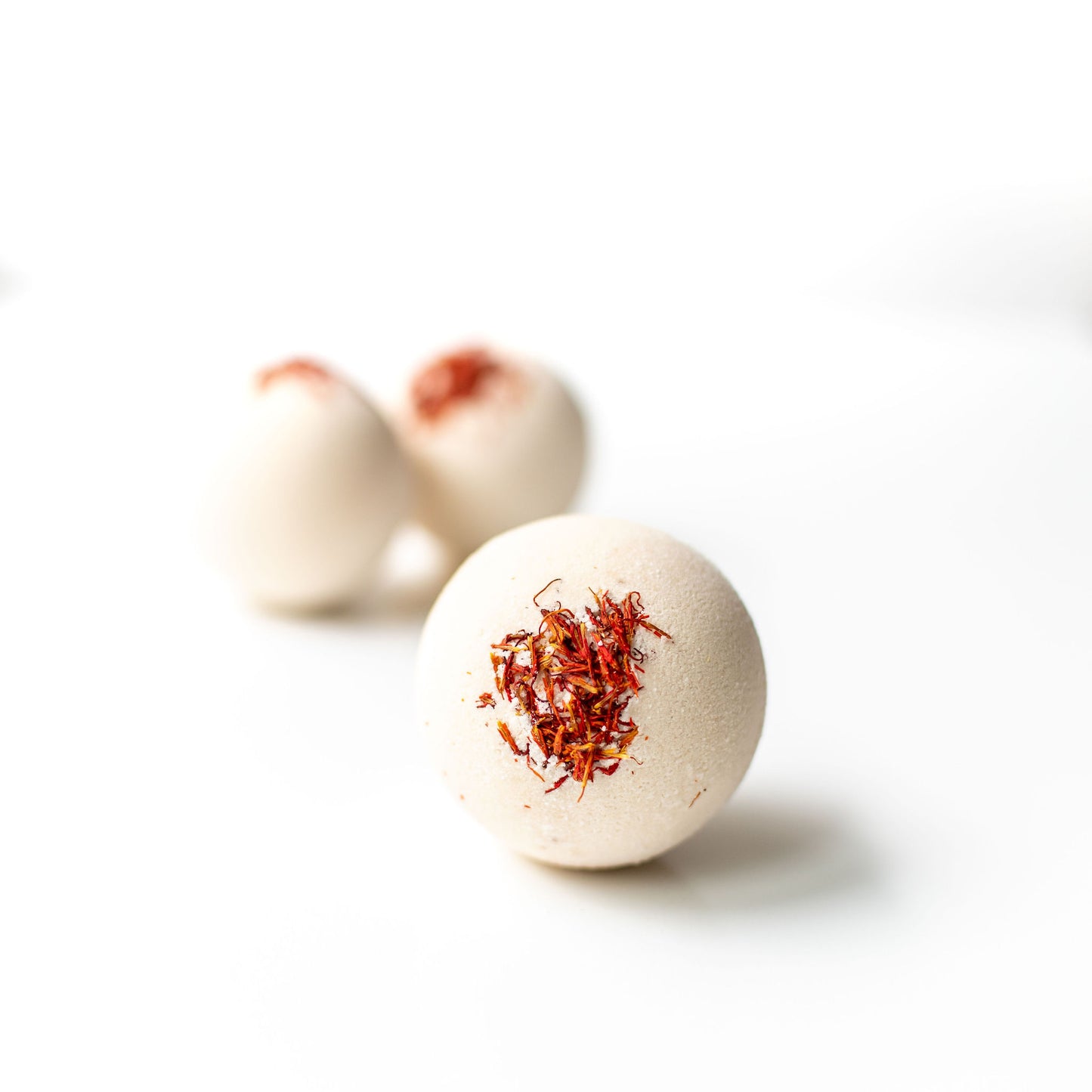 Bath bombs with red specks on a white background