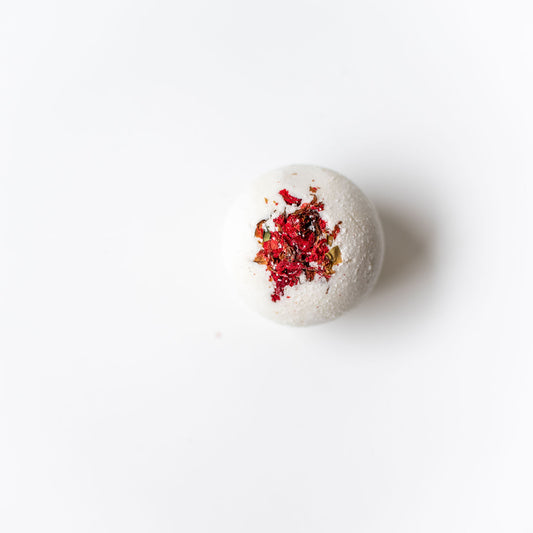 Bath bomb with red and orange toppings on a white background