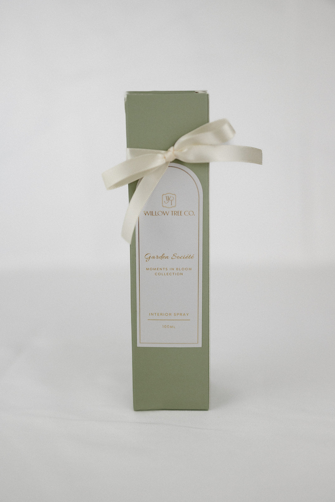 Green gift box with a white label and ribbon on a light gray background