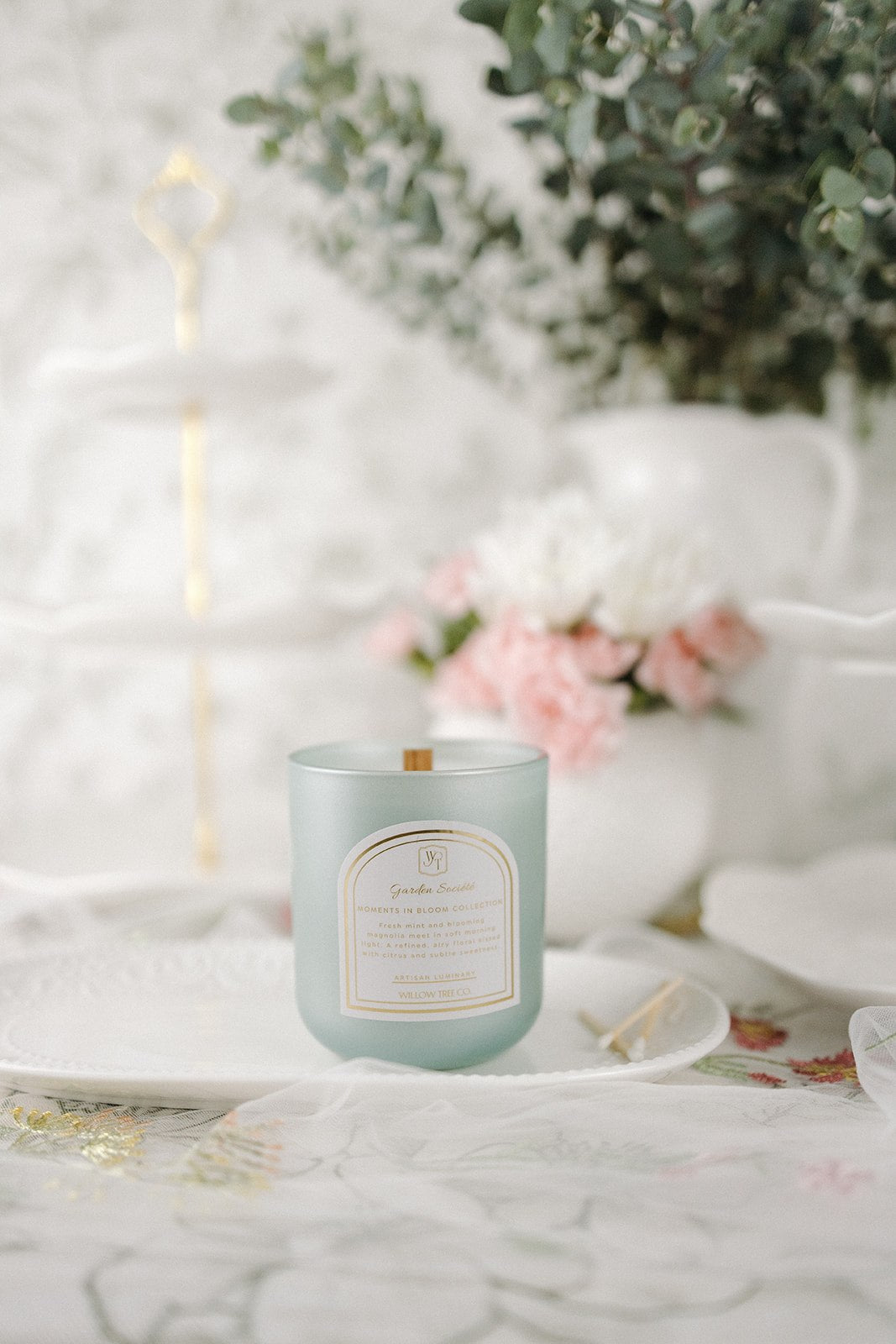 Mint green candle with a label on a white surface with decorative elements