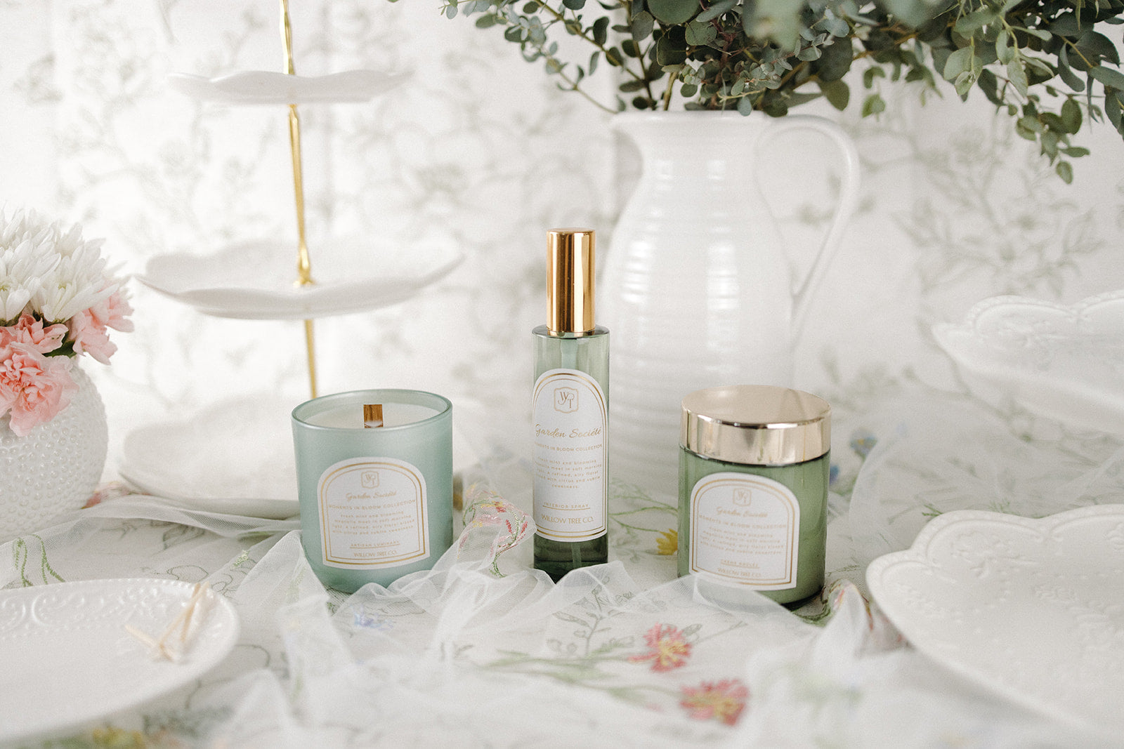 interior spray, body cream, and a candle on a white surface with floral decorations