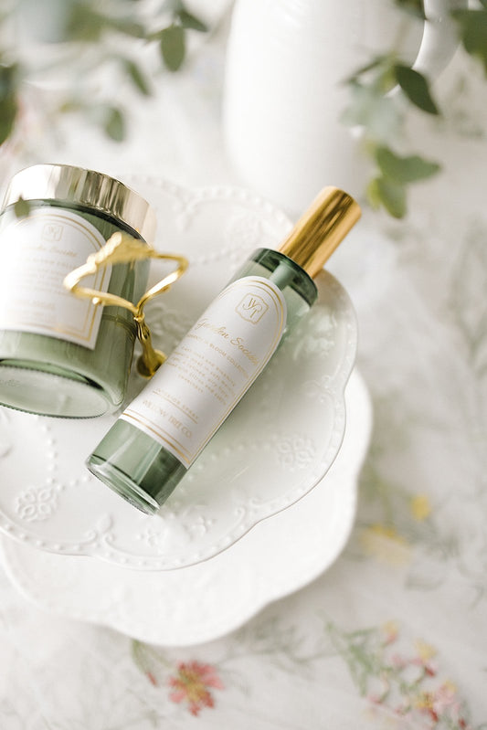 Skincare products including a bottle and jar on a white surface with greenery in the background.