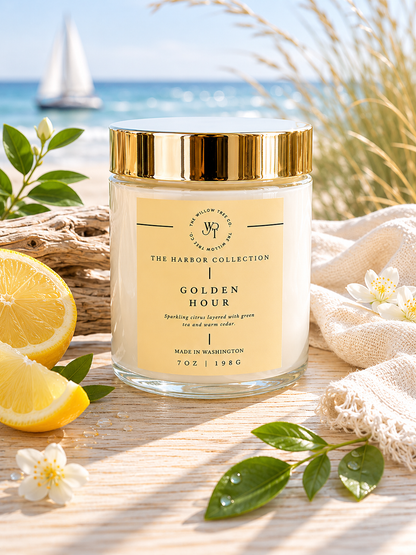 Candle jar labeled 'Golden Hour' from The Harbor Collection on a beach setting with lemons and flowers.