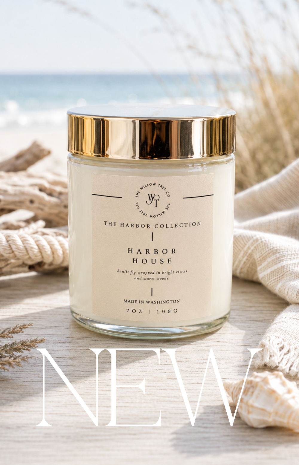 Luxury coastal candle with a soft sand-colored label styled beside driftwood, rope, and seashells with an airy ocean backdrop.