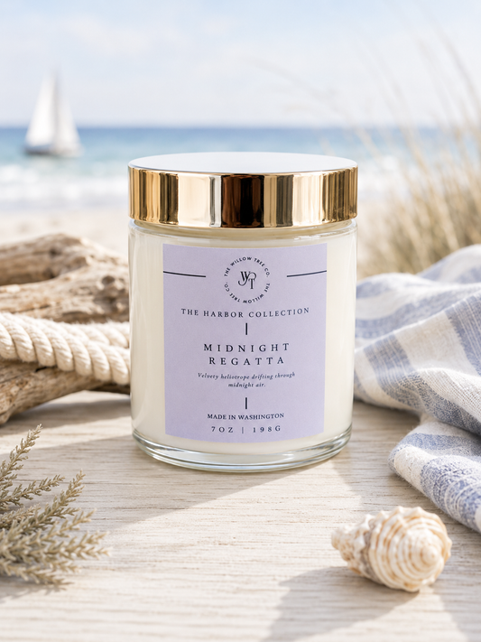 Luxury coastal candle with a soft lavender label styled beside driftwood, rope, and seashells with an airy ocean backdrop.