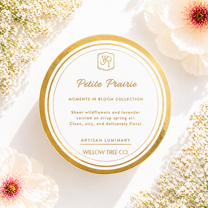 Petite Prairie luxury spring candle with gold lid surrounded by soft wildflowers and airy floral styling in bright natural light