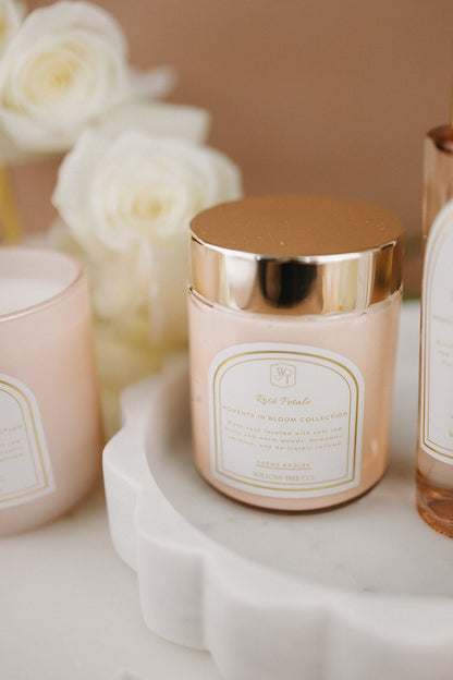 Body cream with gold lid and decorative label on a white surface with flowers in the background