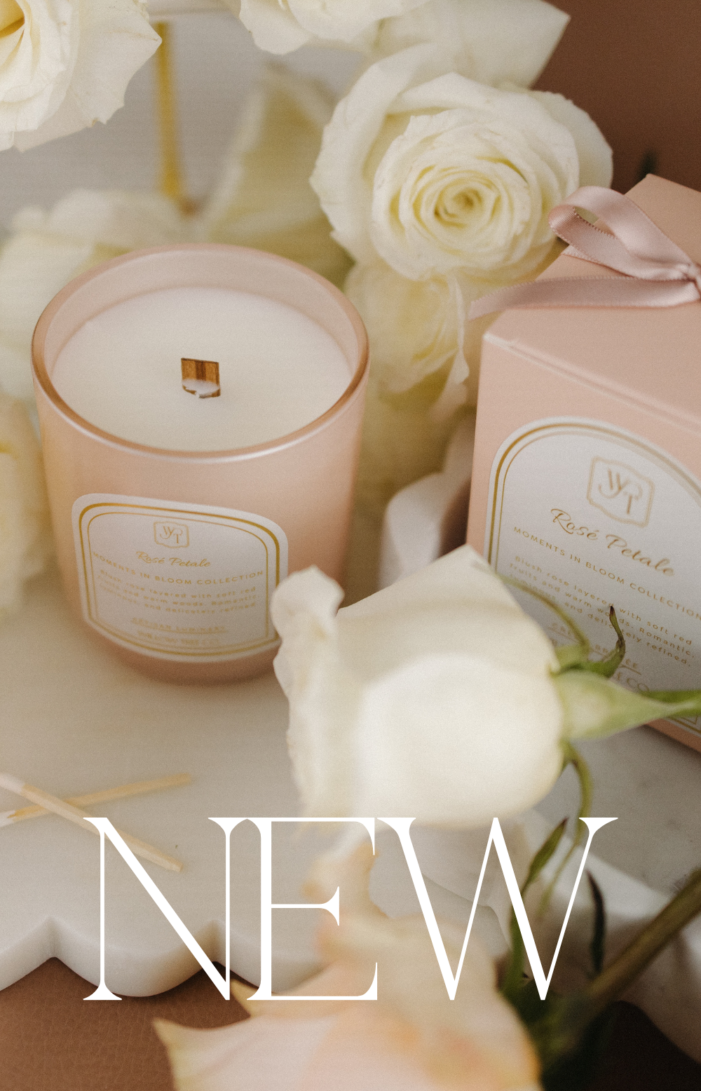 Pink candle with a decorative box and white roses on a light surface.