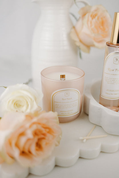 Candle and interior spray with floral arrangement on a light surface