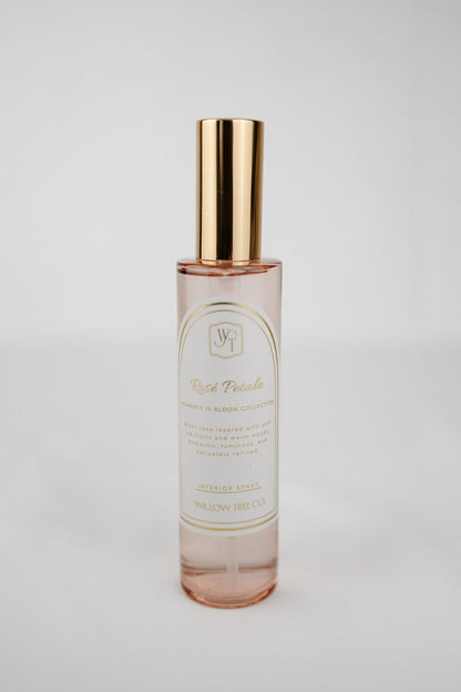 Pink interior spray bottle with gold cap and white label on a light gray background