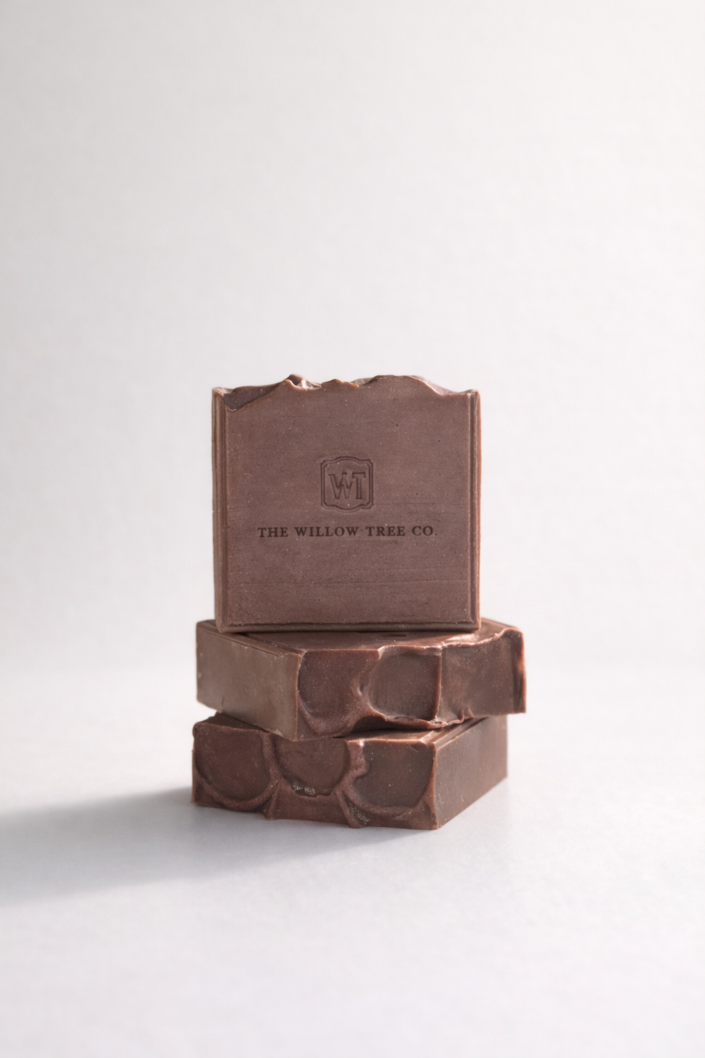 Stack of brown soap bars with a visible brand logo on a white background